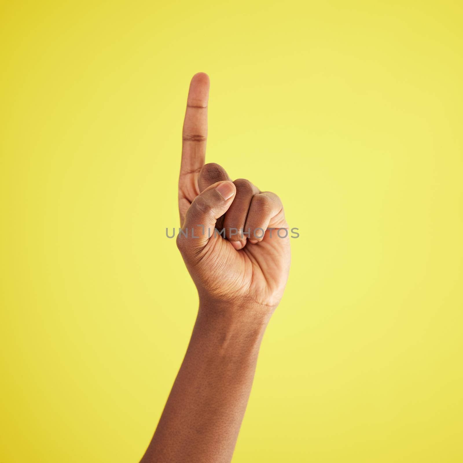 Ill do it. Studio shot of an unrecognisable man pointing upwards against a yellow background. by YuriArcurs