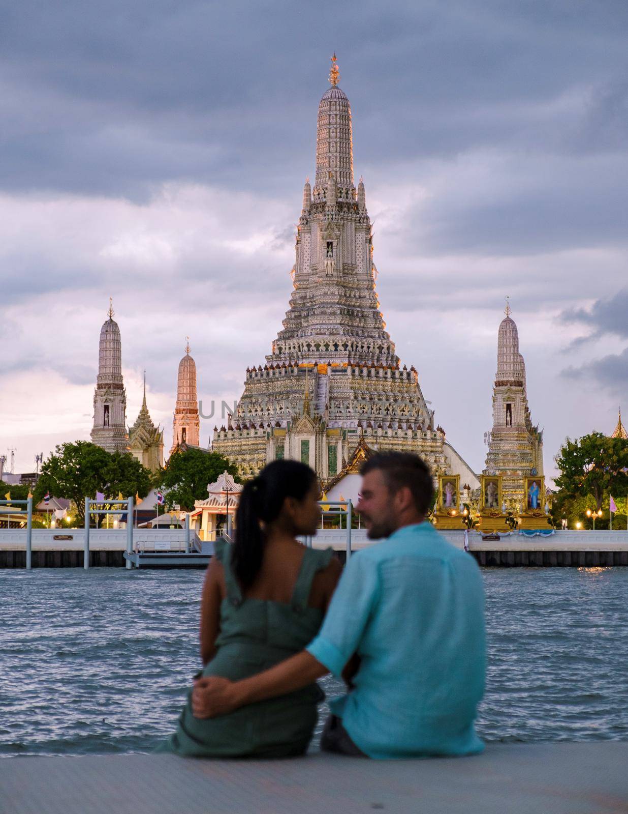 Out of focus blur couple of Asian women and European men watching the sunset at Wat Arun temple in Bangkok Thailand, Temple of Dawn, Buddhist temple alongside the Chao Phraya River.