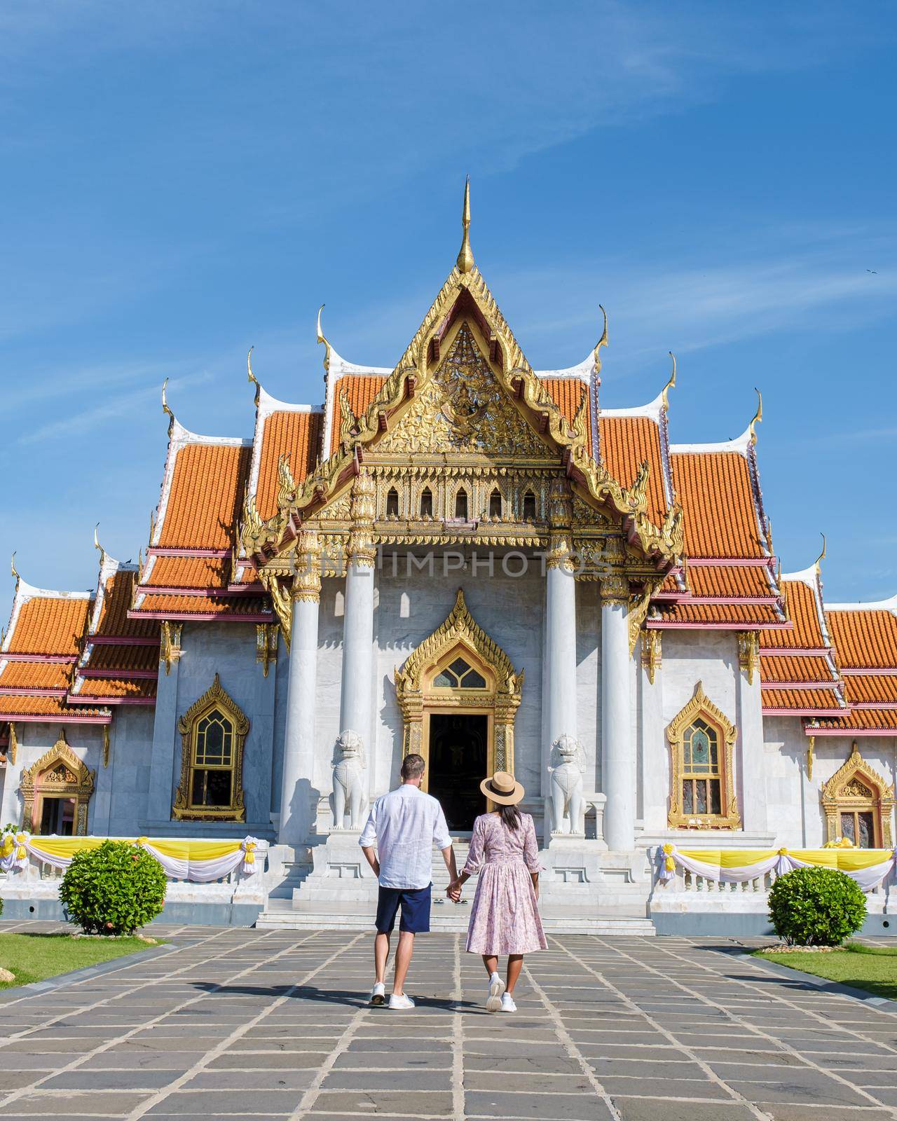 Wat Benchamabophit temple in Bangkok Thailand, The Marble temple in Bangkok. Asian woman with hat and European men visiting a temple, a couple on a city trip in Bangkok