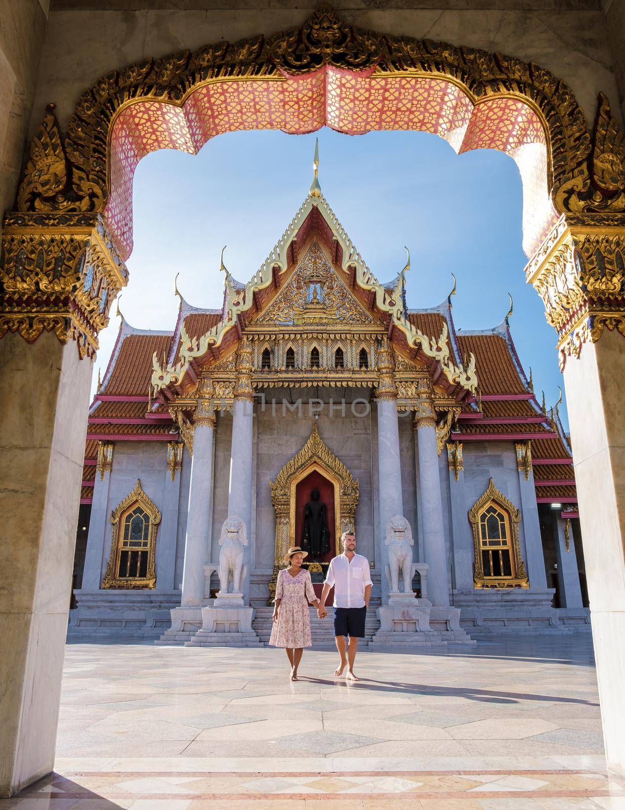 Wat Benchamabophit temple in Bangkok Thailand, The Marble temple in Bangkok. Asian woman with hat and European men visiting a temple, a couple on a city trip in Bangkok