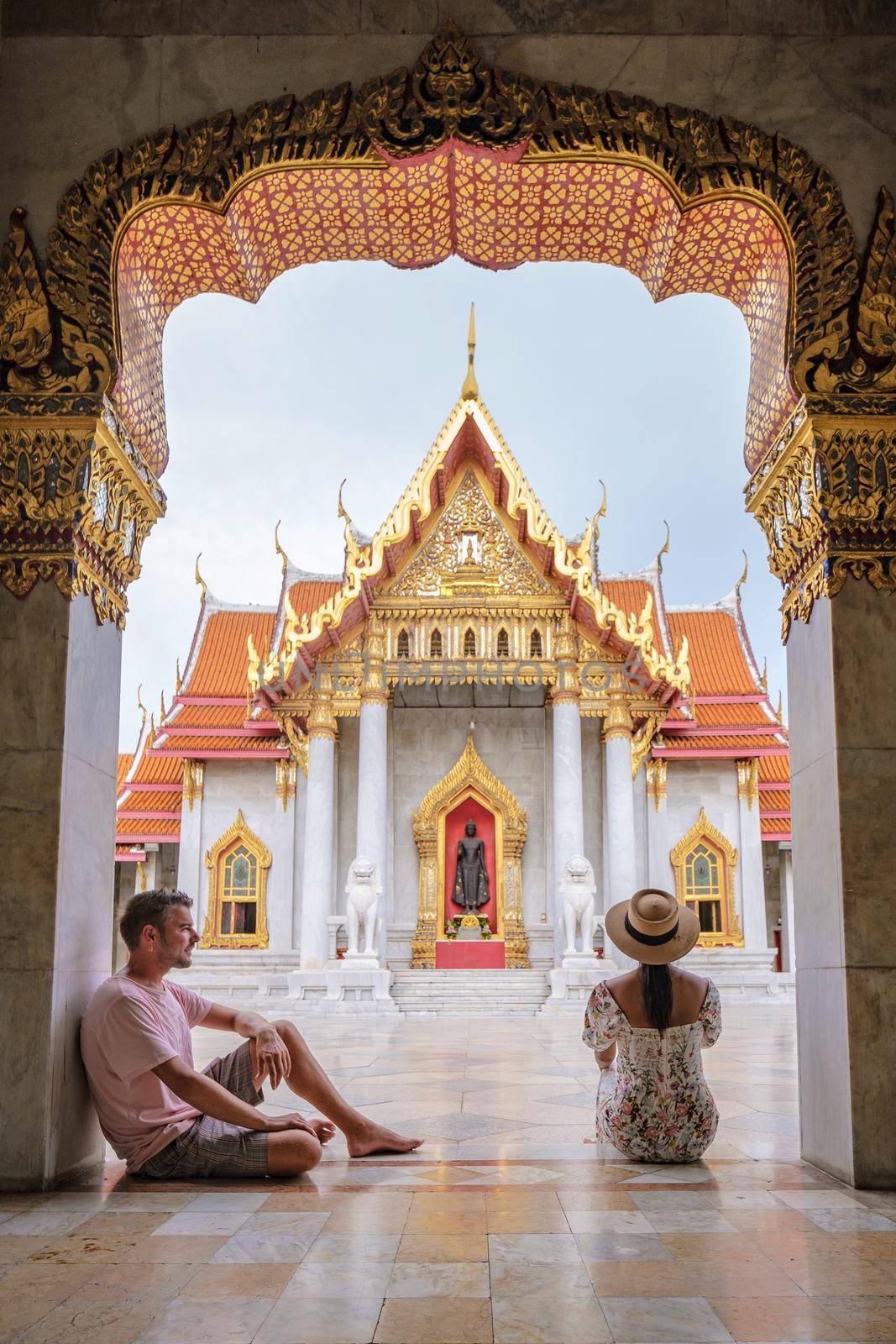 Wat Benchamabophit temple in Bangkok Thailand, The Marble temple in Bangkok. Asian woman with hat and European men visiting a temple, a couple on a city trip in Bangkok