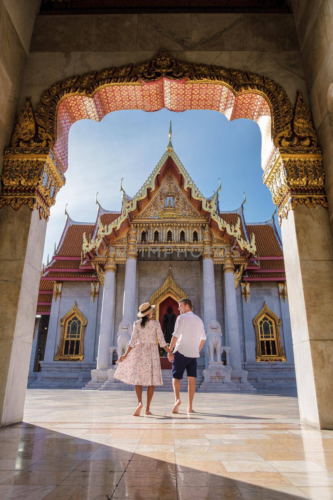 Wat Benchamabophit temple in Bangkok Thailand, The Marble temple in Bangkok. Asian woman with hat and European men visiting a temple, a couple on a city trip in Bangkok