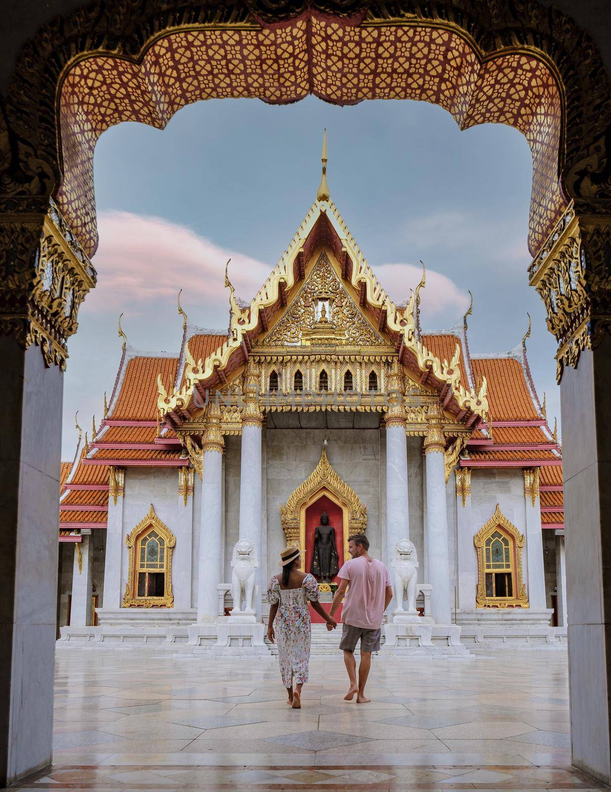 Wat Benchamabophit temple in Bangkok Thailand, The Marble temple in Bangkok. Asian woman with hat and European men visiting a temple, a couple on a city trip in Bangkok