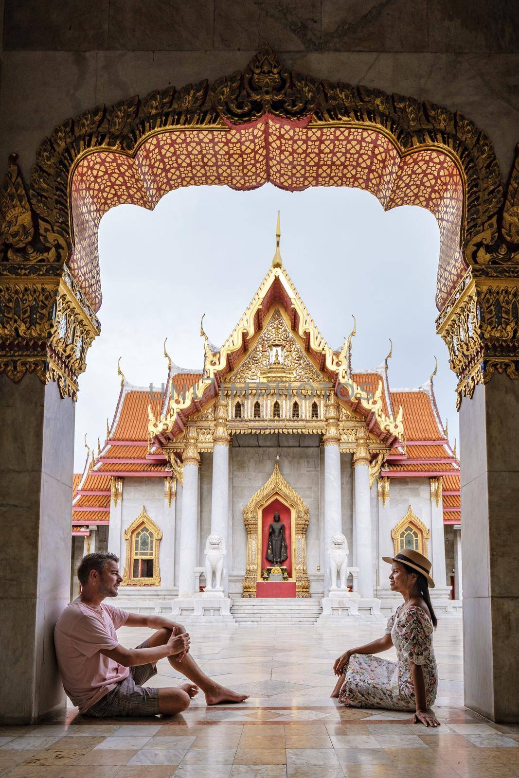 Wat Benchamabophit temple in Bangkok Thailand, The Marble temple in Bangkok. Asian woman with hat and European men visiting a temple, a couple on a city trip in Bangkok