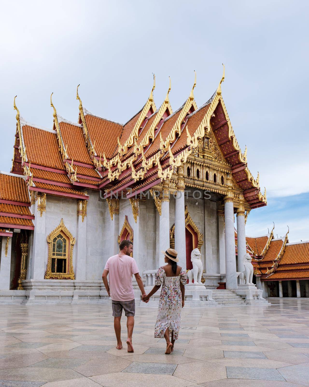 Wat Benchamabophit temple in Bangkok Thailand, The Marble temple in Bangkok. Asian woman with hat and European men visiting a temple, a couple on a city trip in Bangkok