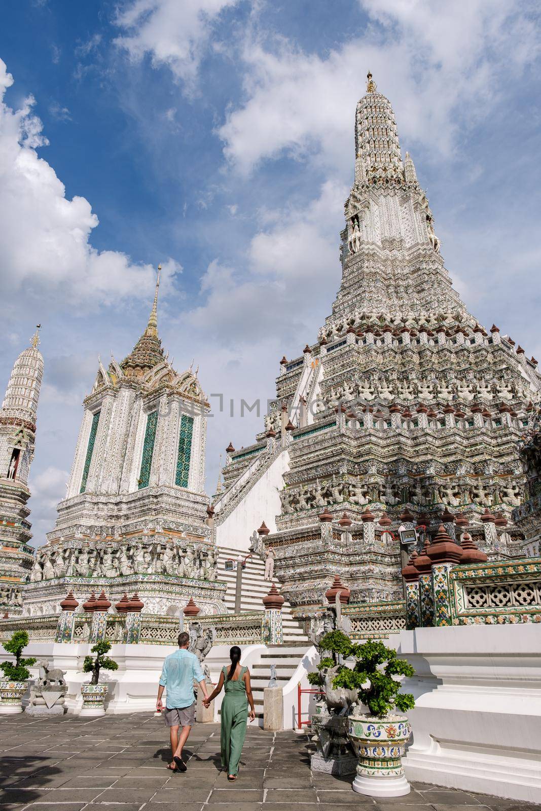 Wat Arun temple Bangkok Thailand, Temple of Dawn, Buddhist temple alongside Chao Phraya River.Beautiful Wat Arun at dusk evening sunset,couple Asian woman and European men visiting temple in Bangkok