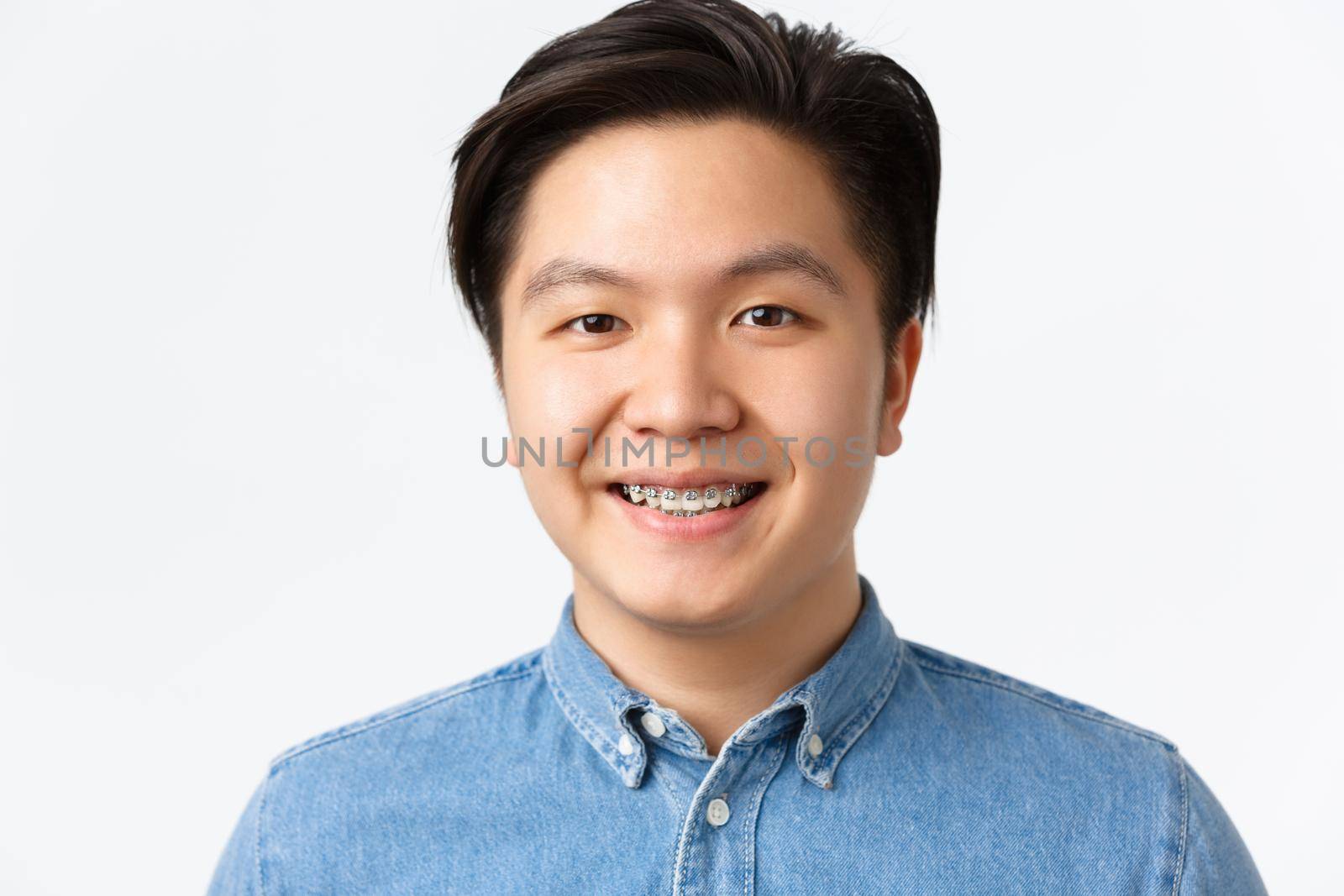 Orthodontics, dental care and stomatology concept. Close-up portrait of handsome asian man with teeth braces, smiling pleased, looking hopeful and happy, standing white background.