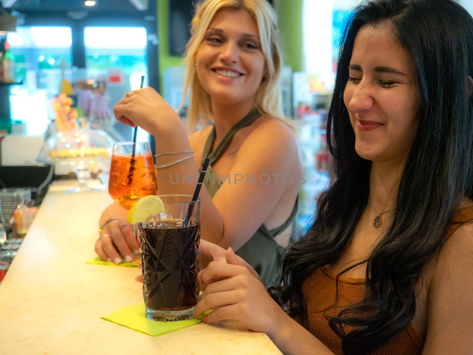 caucasian and latino female friends at the bar drinking spritz and cola libre by verbano