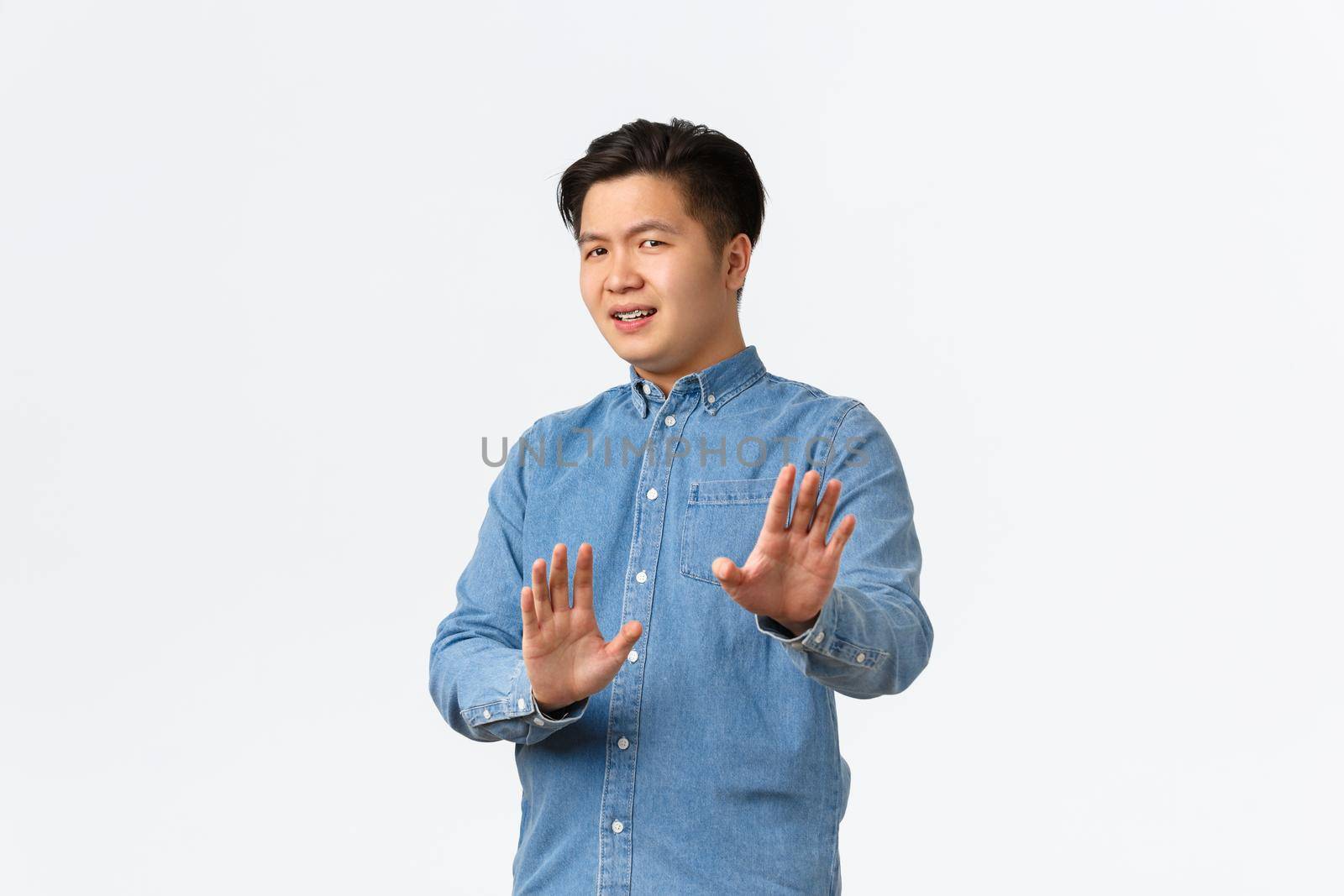 No thank you. Unamused and bothered asian man step away from trouble, raising hands in stop gesture, refusing or rejecting ofer, denying something bad, standing white background by Benzoix