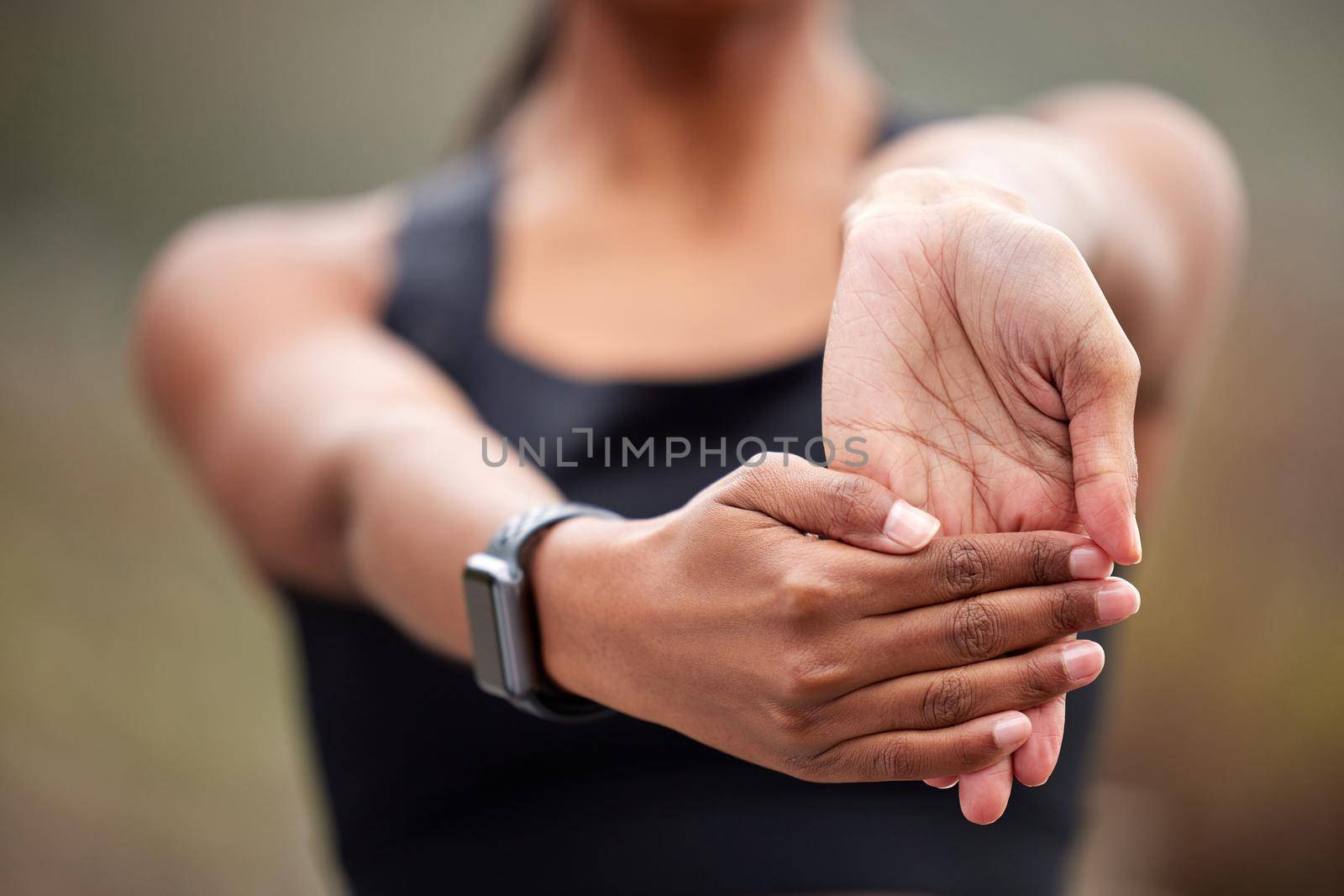 A healthy lifestyle is physically demanding. an unrecognizable woman holding her hand out and moving her wrist while jogging outdoors
