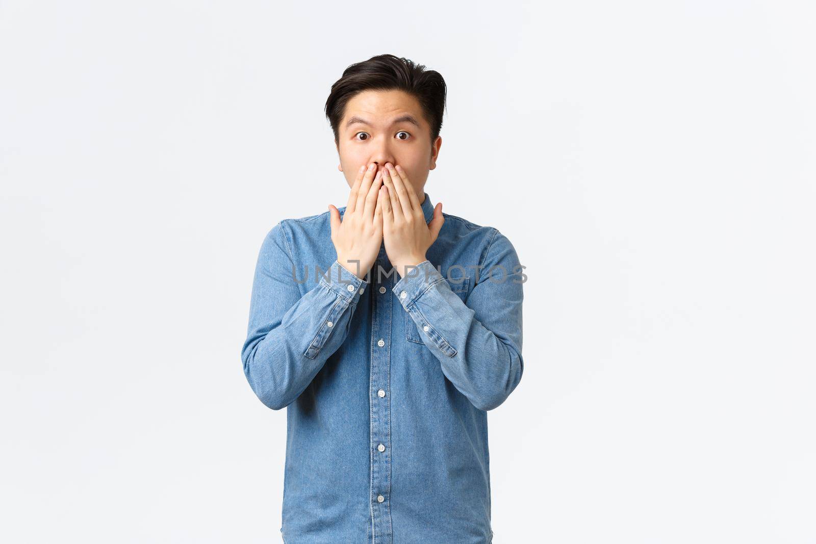 Shocked astounded asian man witness accident, gasping and cover mouth, gossiping with coworkers at office, hear stunning news, standing white background speechless by Benzoix