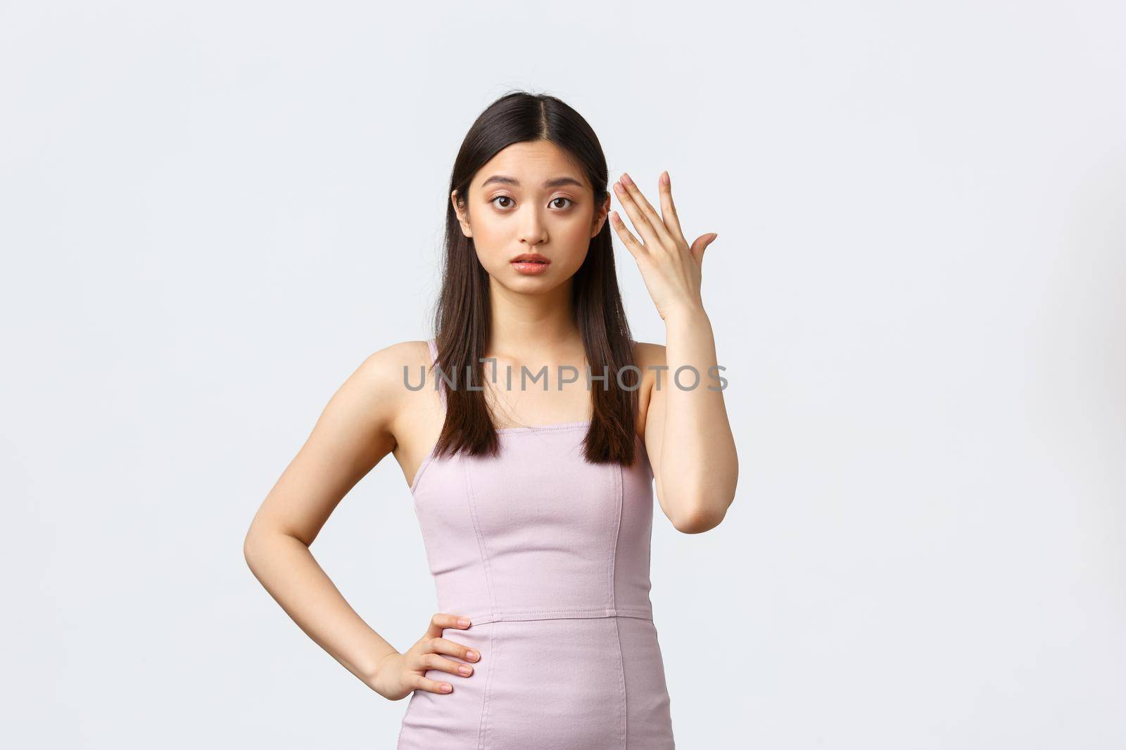 Luxury women, party and holidays concept. Annoyed young asian woman in evening dress, pointing at head and looking irritated, fed up listening complain, standing white background by Benzoix