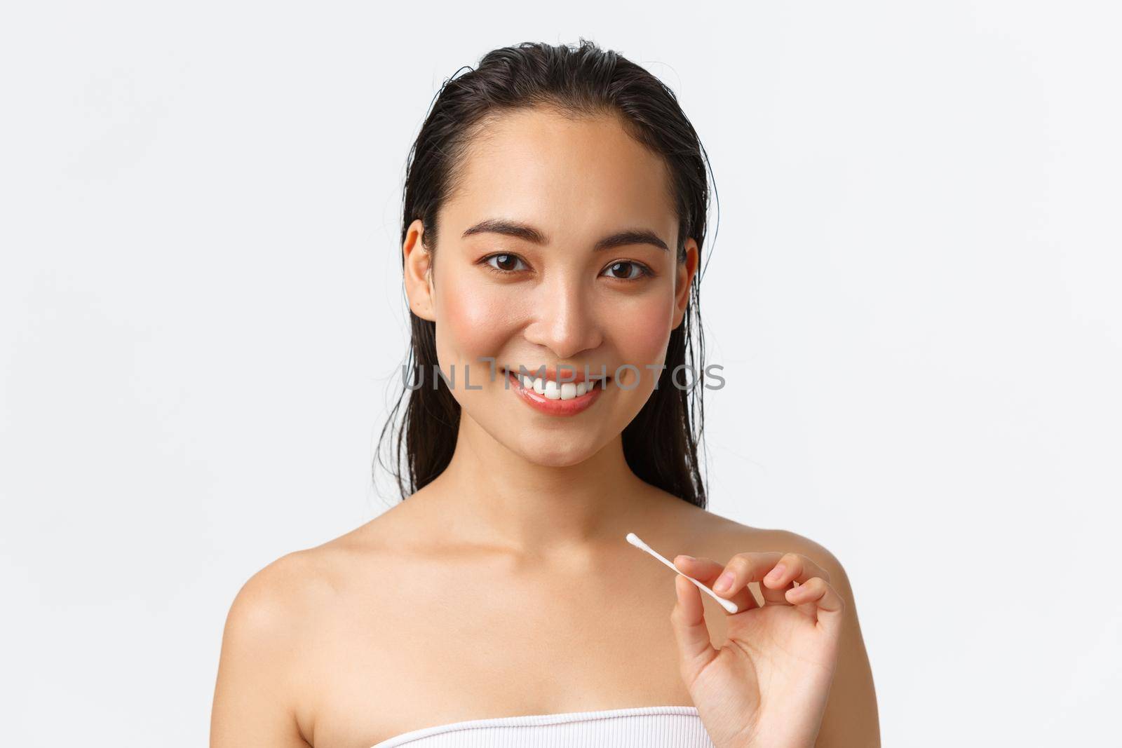 Skincare, women beauty, hygiene and personal care concept. Close-up of beautiful asian girl standing naked in bathroom or shower, holding cotton buds, swabs for ears, standing white background.