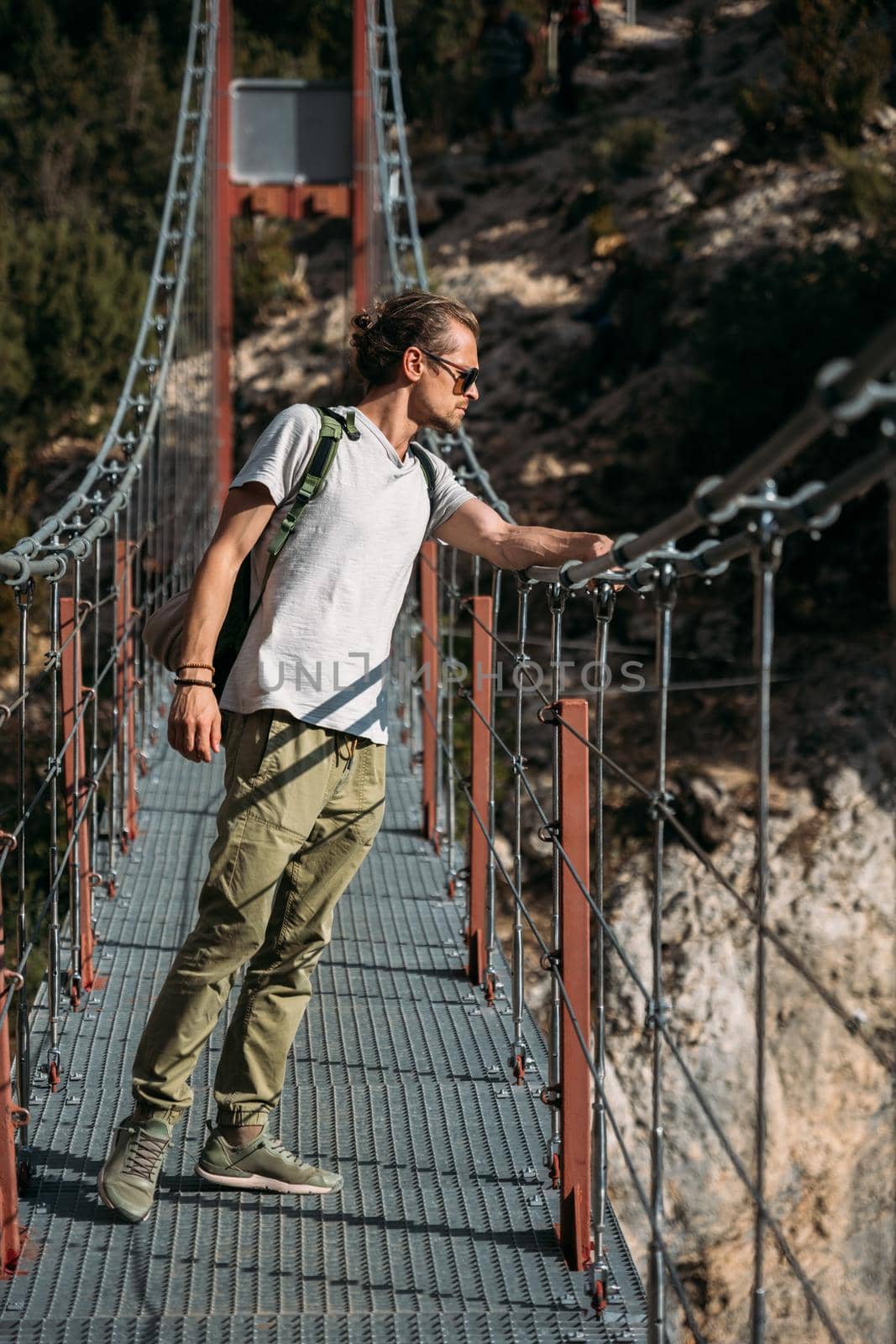 Hiker standing on hanging bridge and looking down to the lake. Travel concept by apavlin