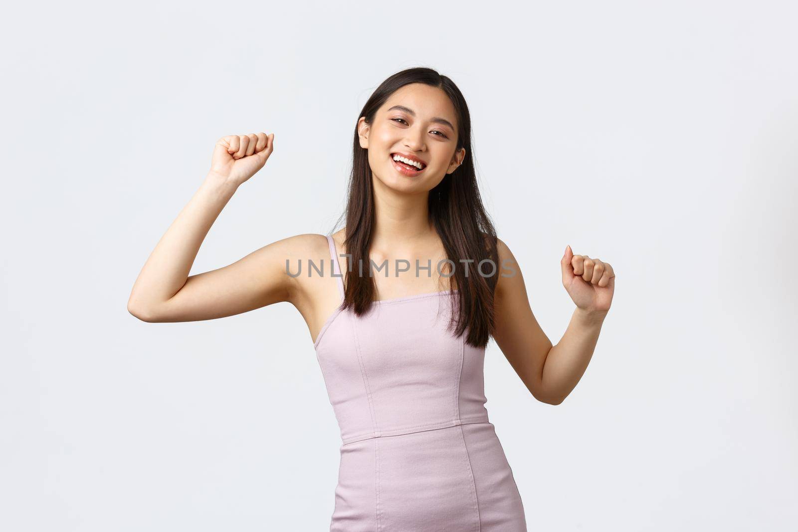 Luxury women, party and holidays concept. Happy excited smiling asian woman do winner dance, become champion, celebrating success, wearing evening dress, rejoicing over good news.