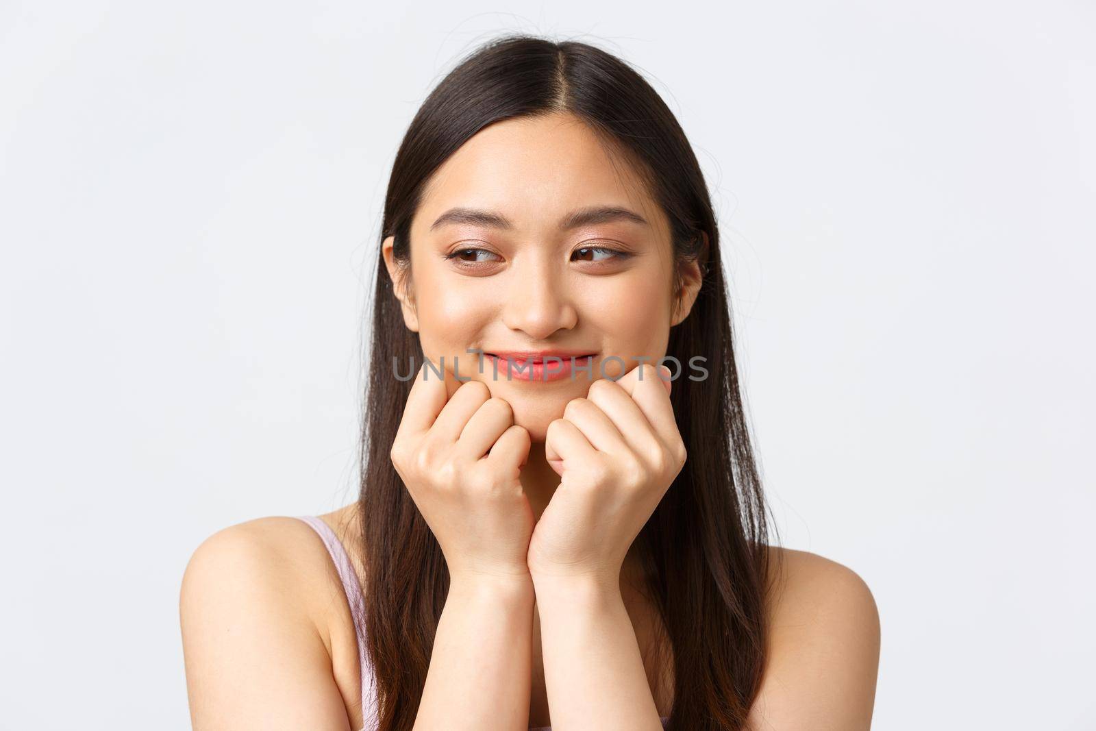 Concept of beauty, fashion and makeup products advertisement. Close-up portrait of adorable romantic asian woman, looking dreamy aside as imaging or remember lovely moment, white background.
