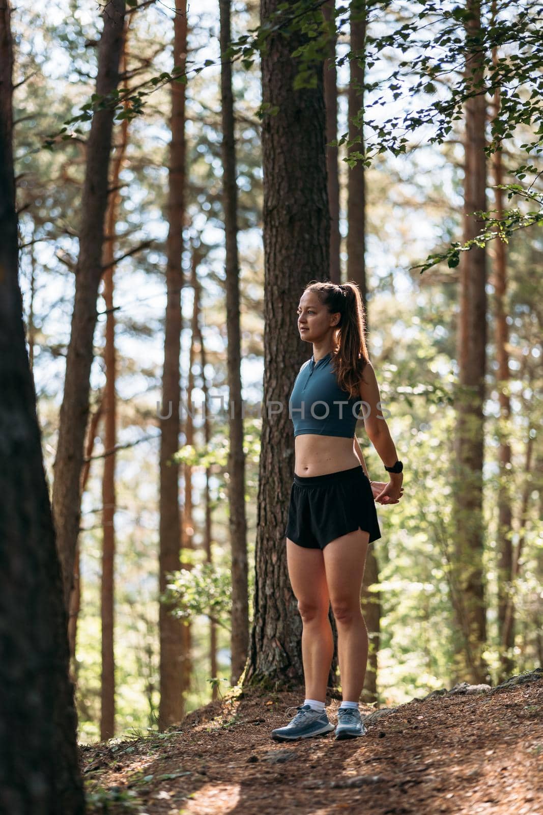 Young female runner stretching and warming up before running at morning forest trail. by apavlin