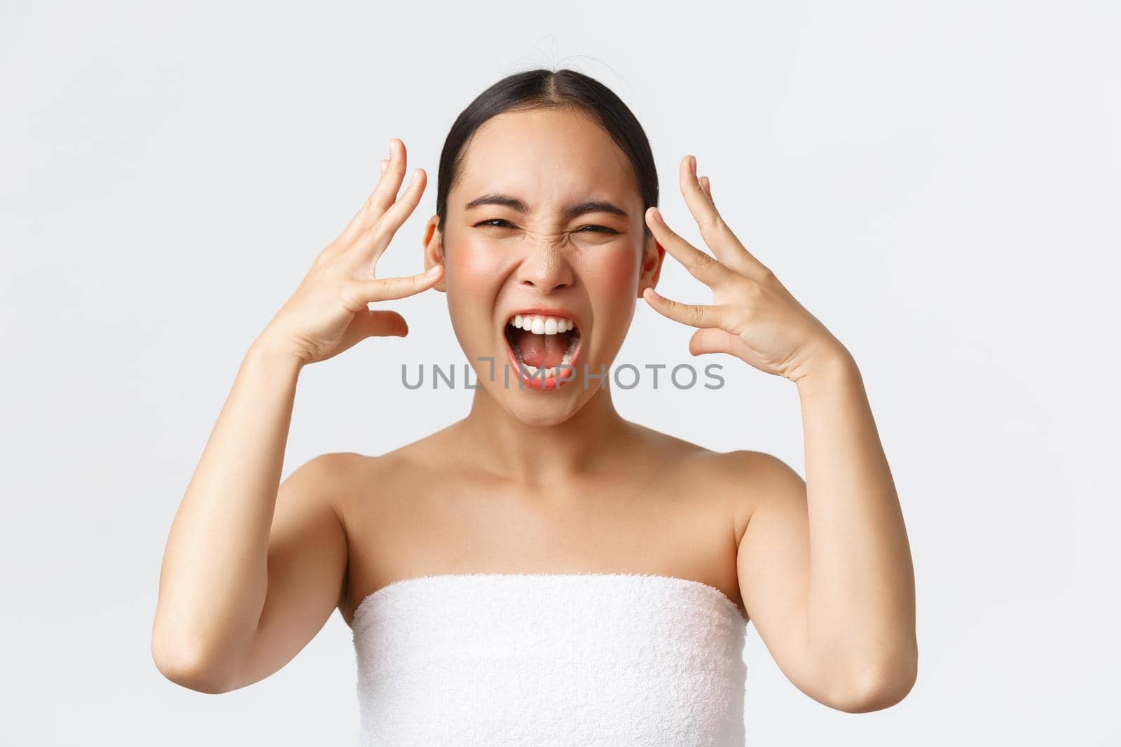 Beauty, cosmetology and spa salon concept. Close-up of outraged, mad distressed asian woman in bath towel screaming and shaking hands near head, feeling furious after bad service in beauty clinic by Benzoix