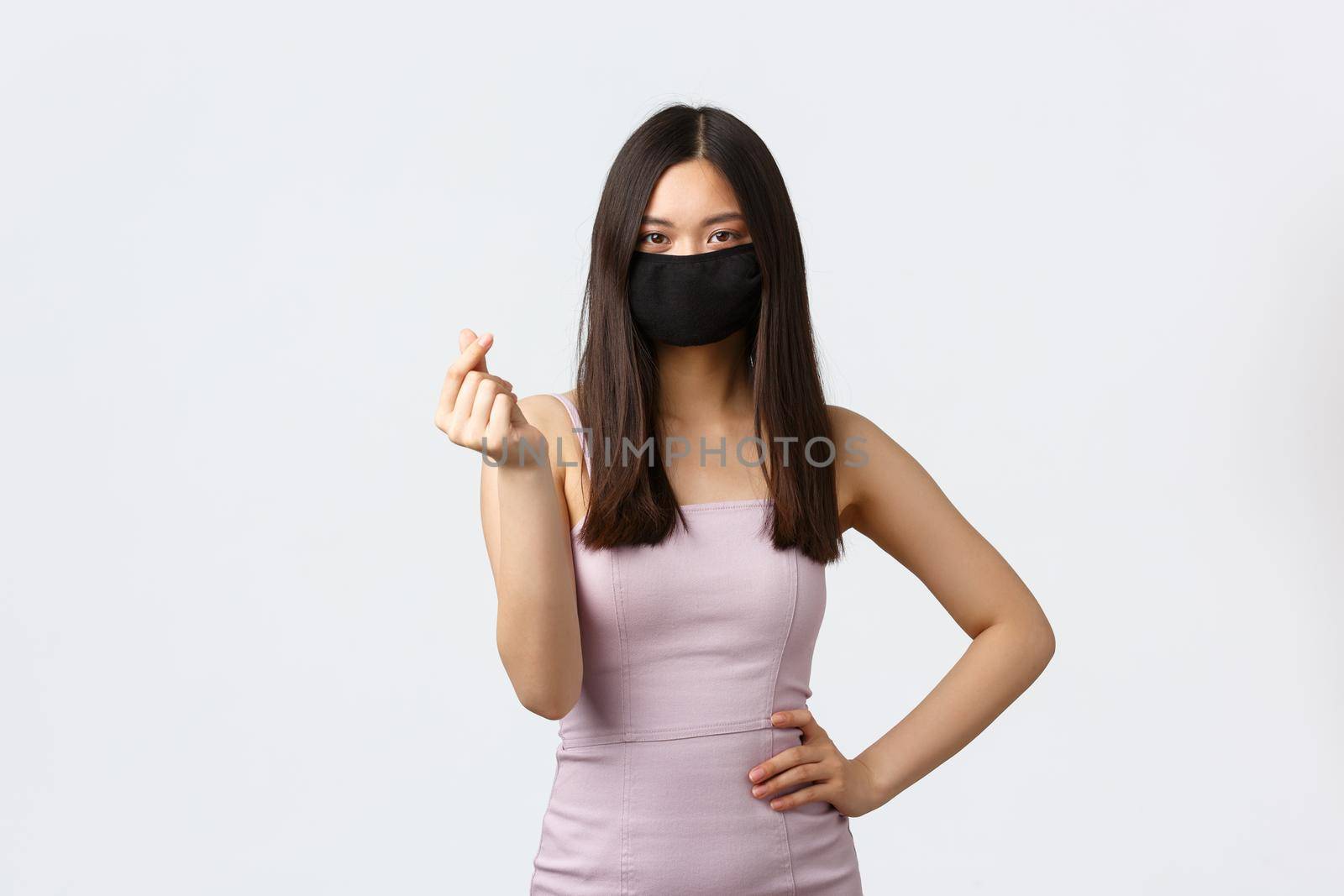 Covid-19, social distancing quarantine and leisure concept. Stylish attractive asian girl in face mask and evening dress, showing korean heart sign, enjoying party and stay safe coronavirus pandemic.