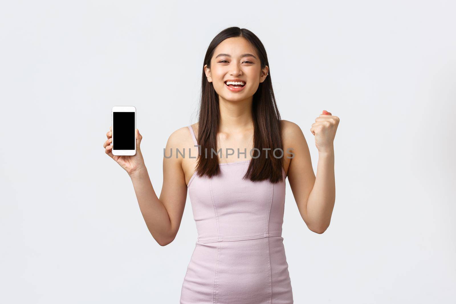 Luxury women, party and holidays concept. Rejoicing, happy asian girl in dress, feeling happy and delighted, got special offer notification on smartphone screen, chanting and show mobile phone by Benzoix
