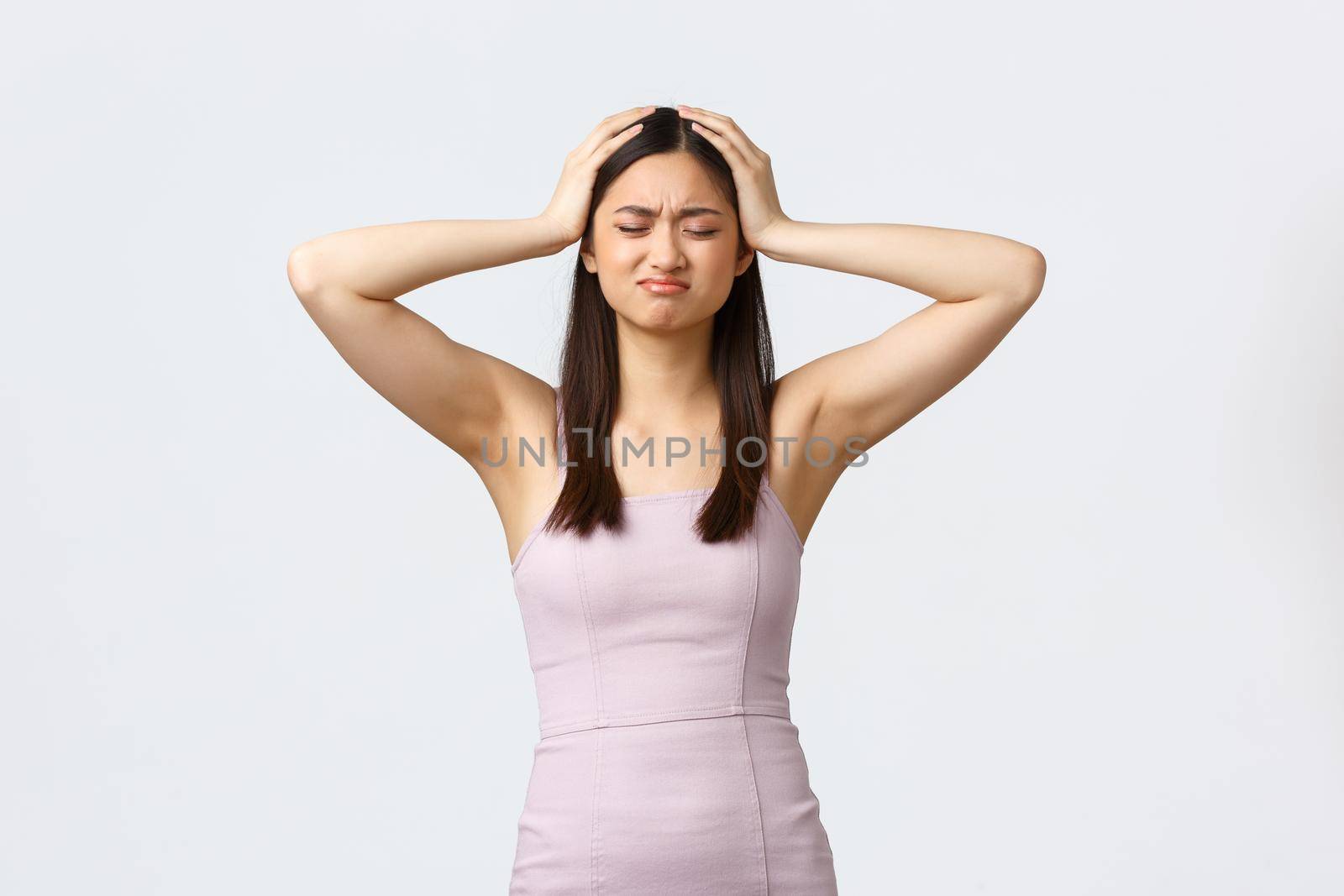 Luxury women, party and holidays concept. Troubled young asian woman in evening dress having lots of troubles and worried, holding head and shaking it in denial, frowning upset, white background.