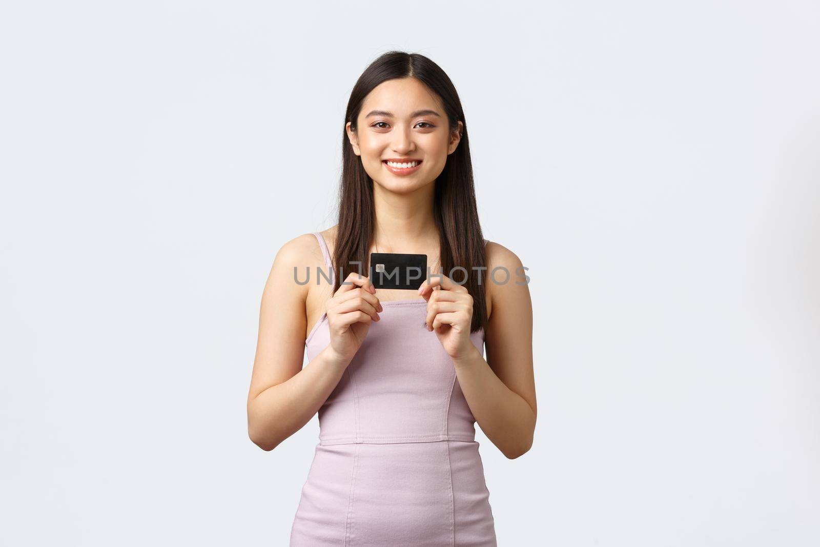 Luxury women, party and holidays concept. Happy rich pretty asian girl in evening dress, showing her brand new credit card, smiling pleased as going shopping, paying for order contactless by Benzoix