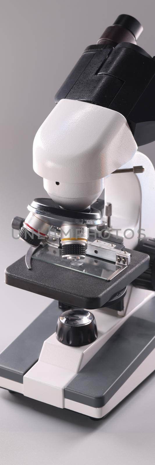 Microscope on gray background Microbiology and healthcare. Scientific equipment for analysis and research.