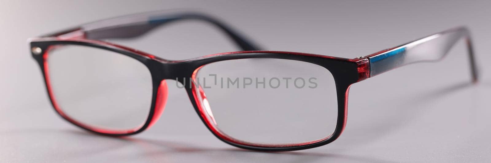 Fashionable plastic glasses red-black on gray background. Choice of stylish optics concept