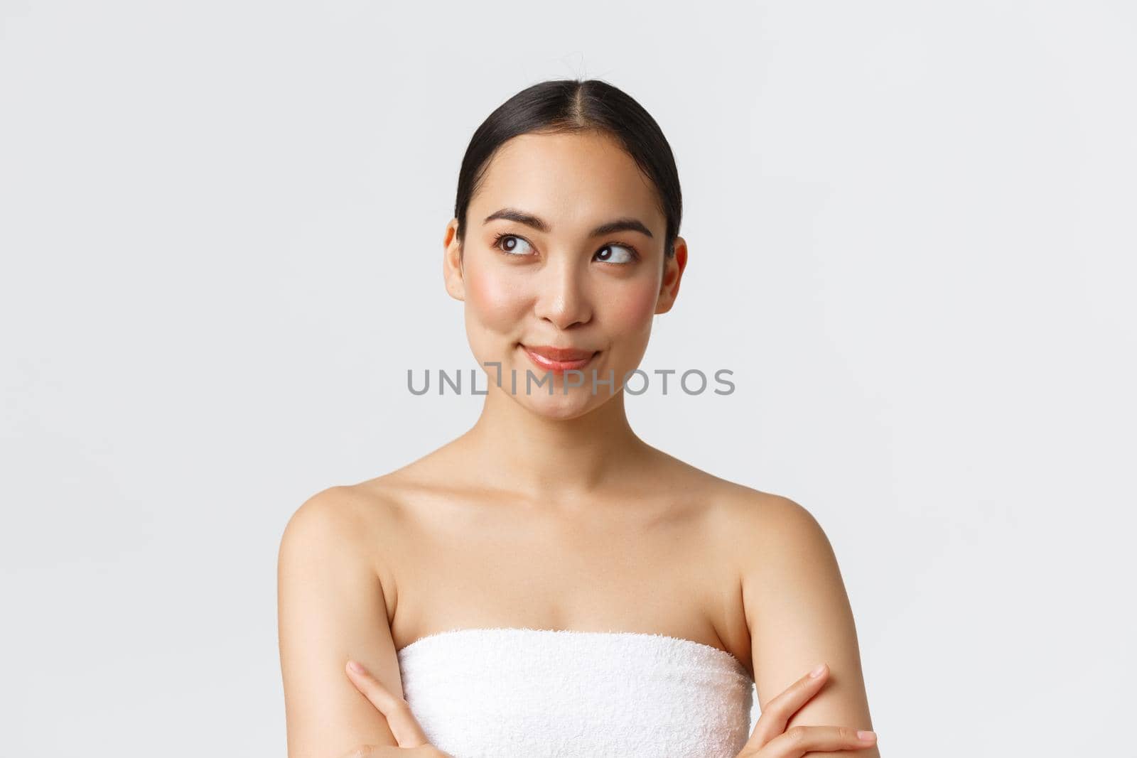 Beauty, cosmetology and spa salon concept. Close-up of confident and pleased smiling gorgeous asian woman, wearing bath towel and smiling as looking left, having idea, white background by Benzoix