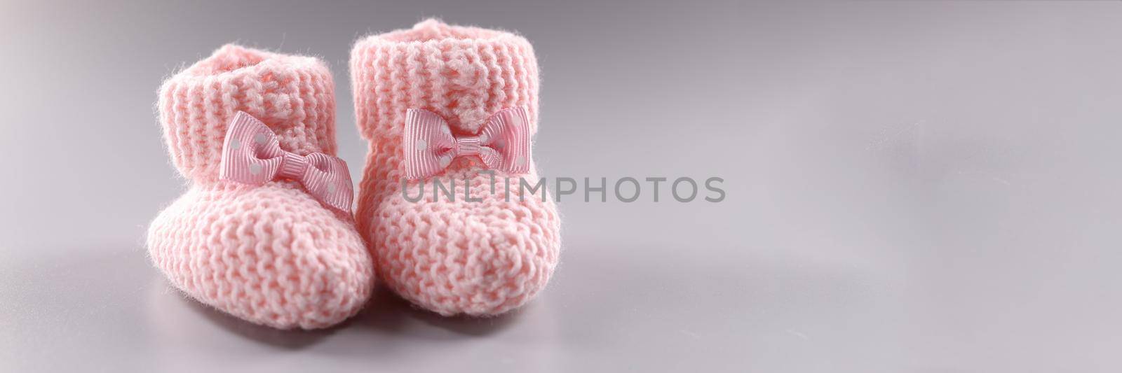 Pink knitted slippers for newborn on gray background by kuprevich