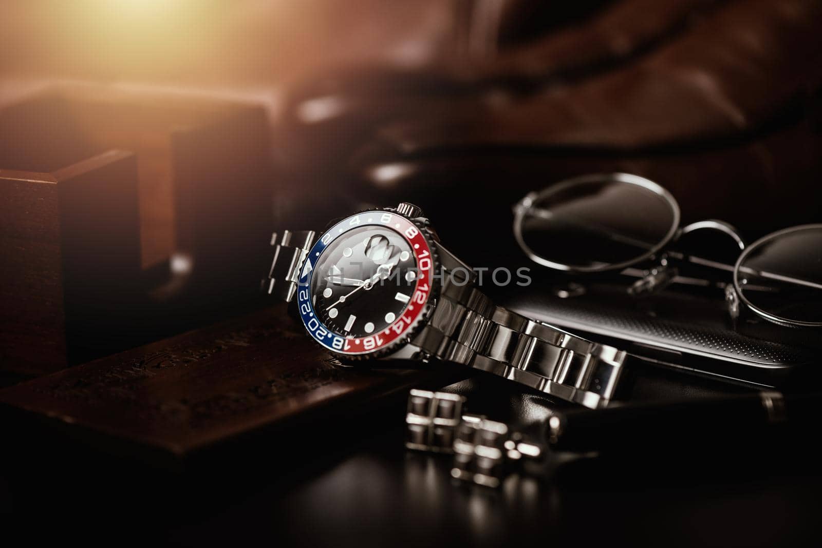men's accessories, closeup at wristwatch with black dial blue-red bezel and stainless steel bracelet.