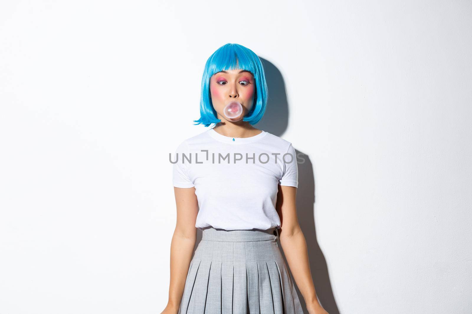 Silly asian girl in blue wig and school uniform, blowing bubble gum with coquettish expression, dressed up for halloween party, standing over white background by Benzoix