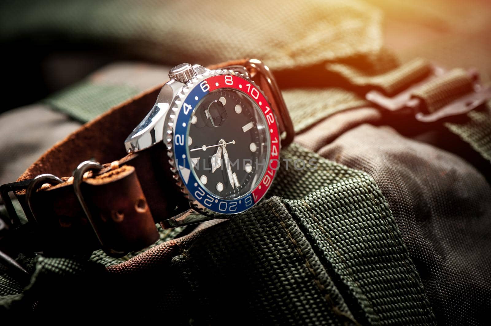 closeup luxury wristwatch for men with black dial blue-red bezel and leather strap. wristwatch with vintage men's objects.