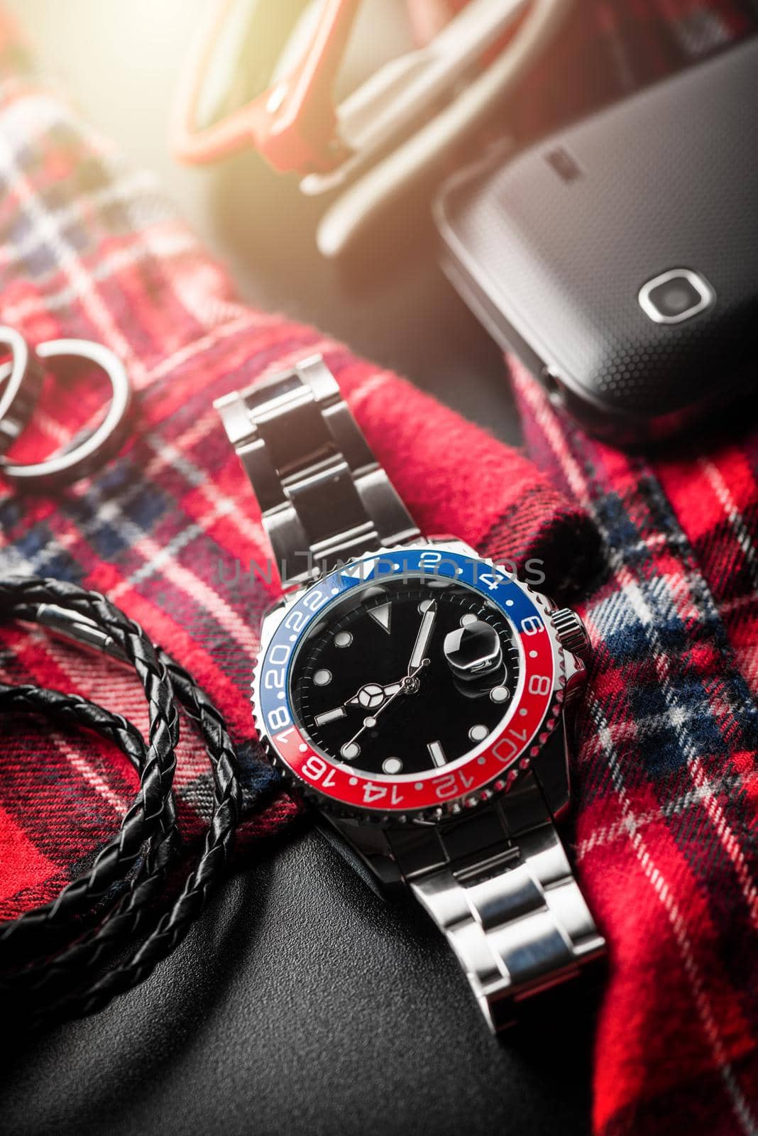 closeup luxury wristwatch for men with black dial blue-red bezel and stainless steel bracelet.