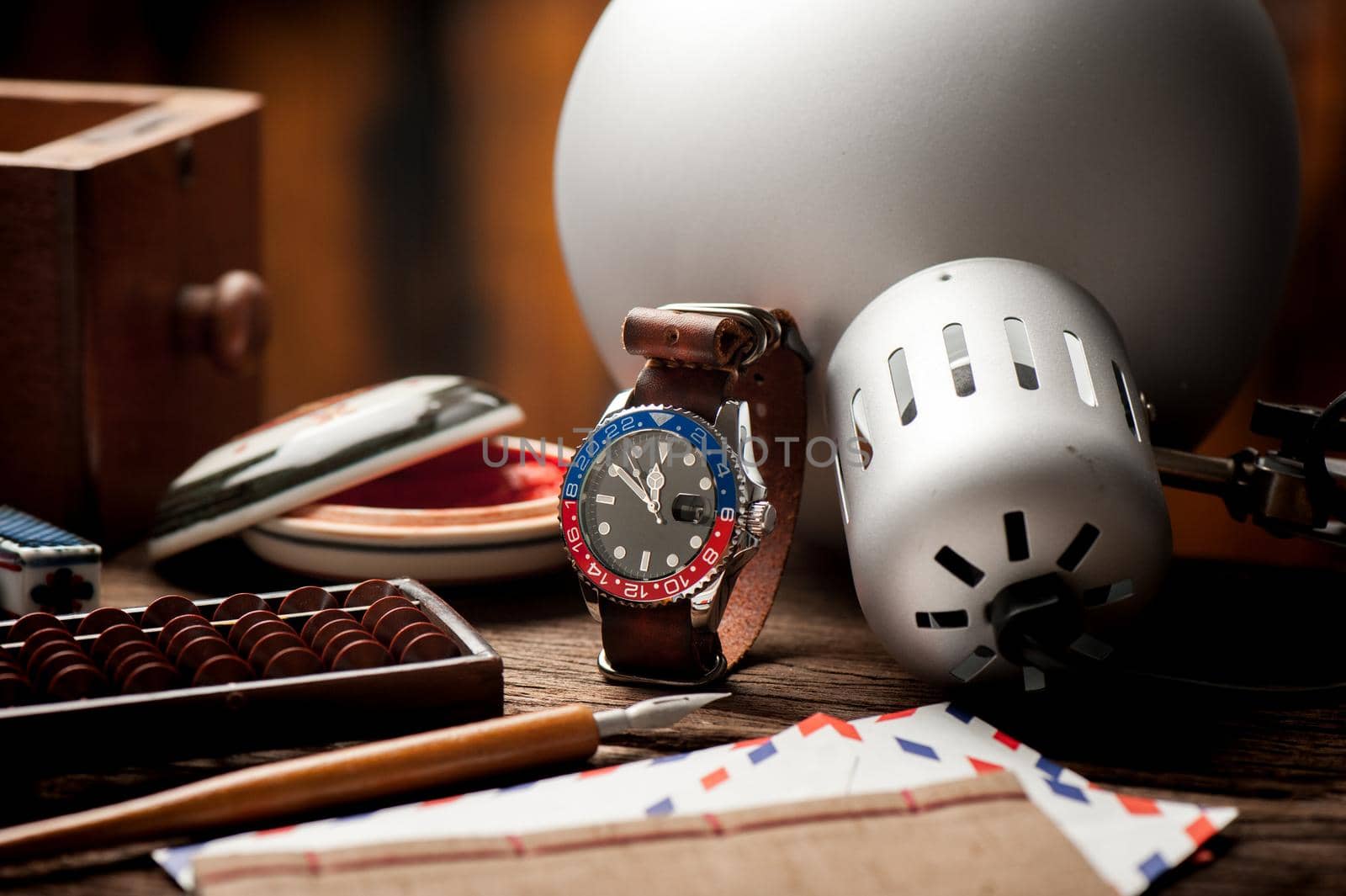 closeup luxury wristwatch for men with black dial blue-red bezel and leather strap.