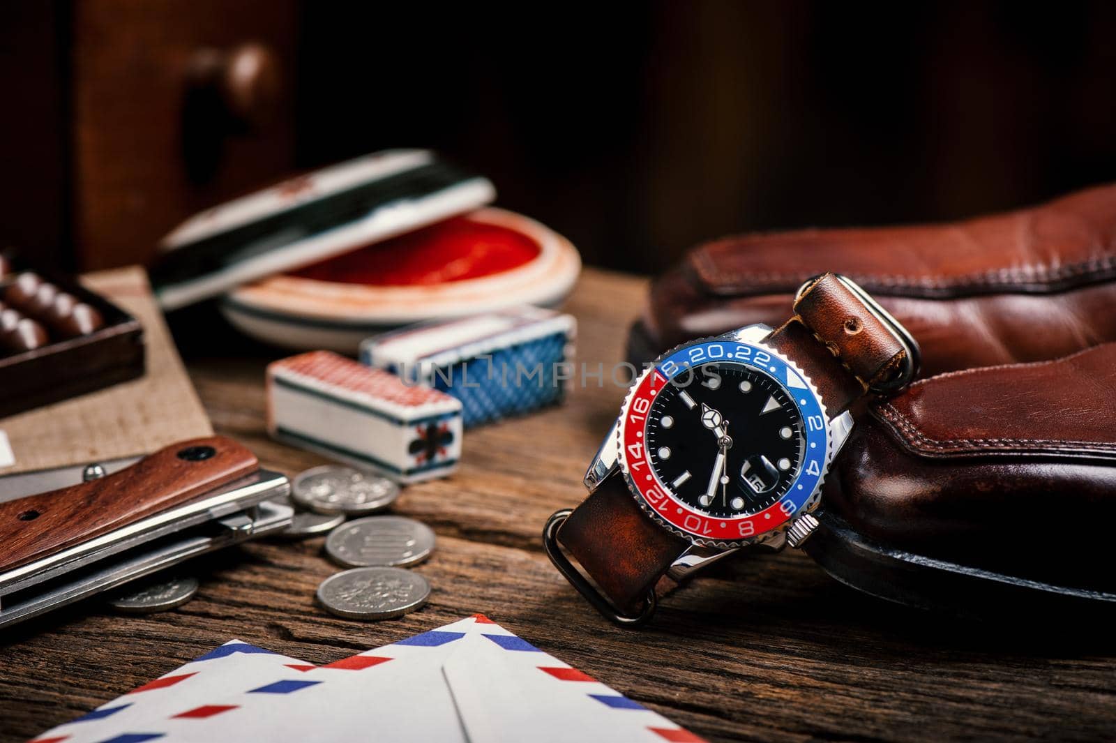 closeup luxury wristwatch for men with black dial blue-red bezel and leather strap.