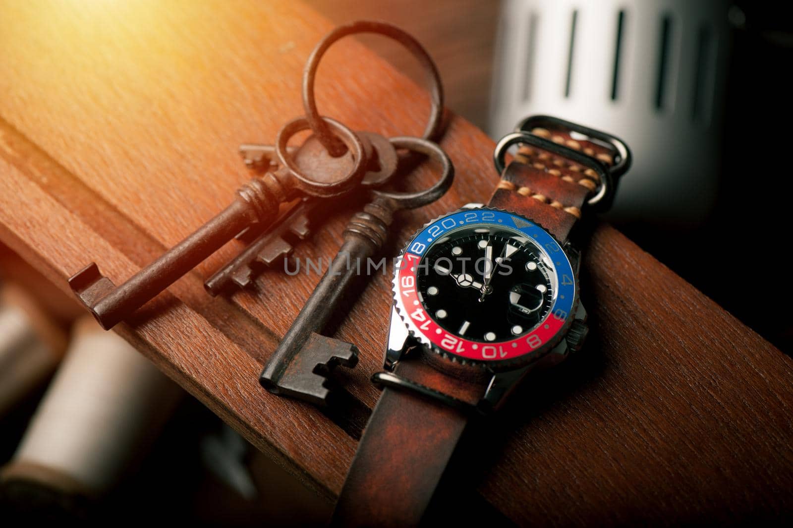 closeup luxury wristwatch for men with black dial blue-red bezel and leather strap.