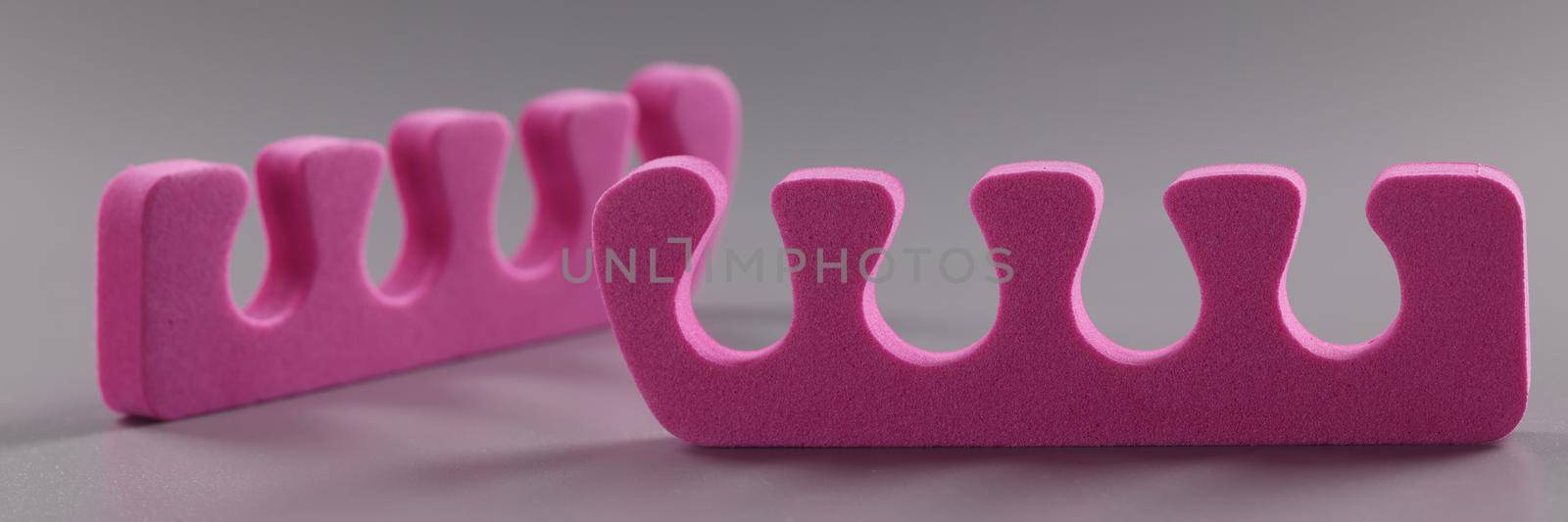 Pink toe divider on gray background. Pedicure accessory by kuprevich