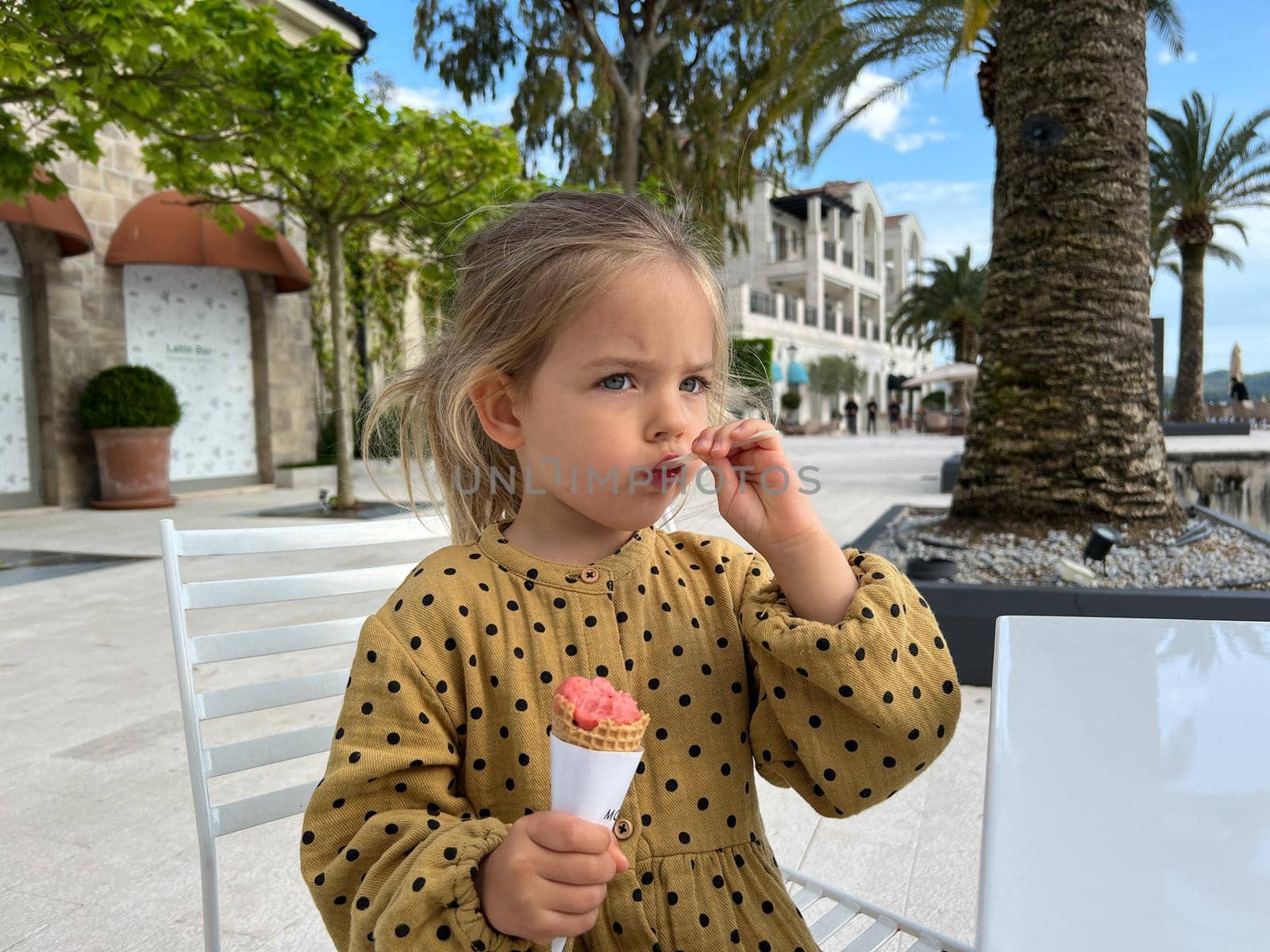 Little girl eating ice cream with a spatula. High quality photo