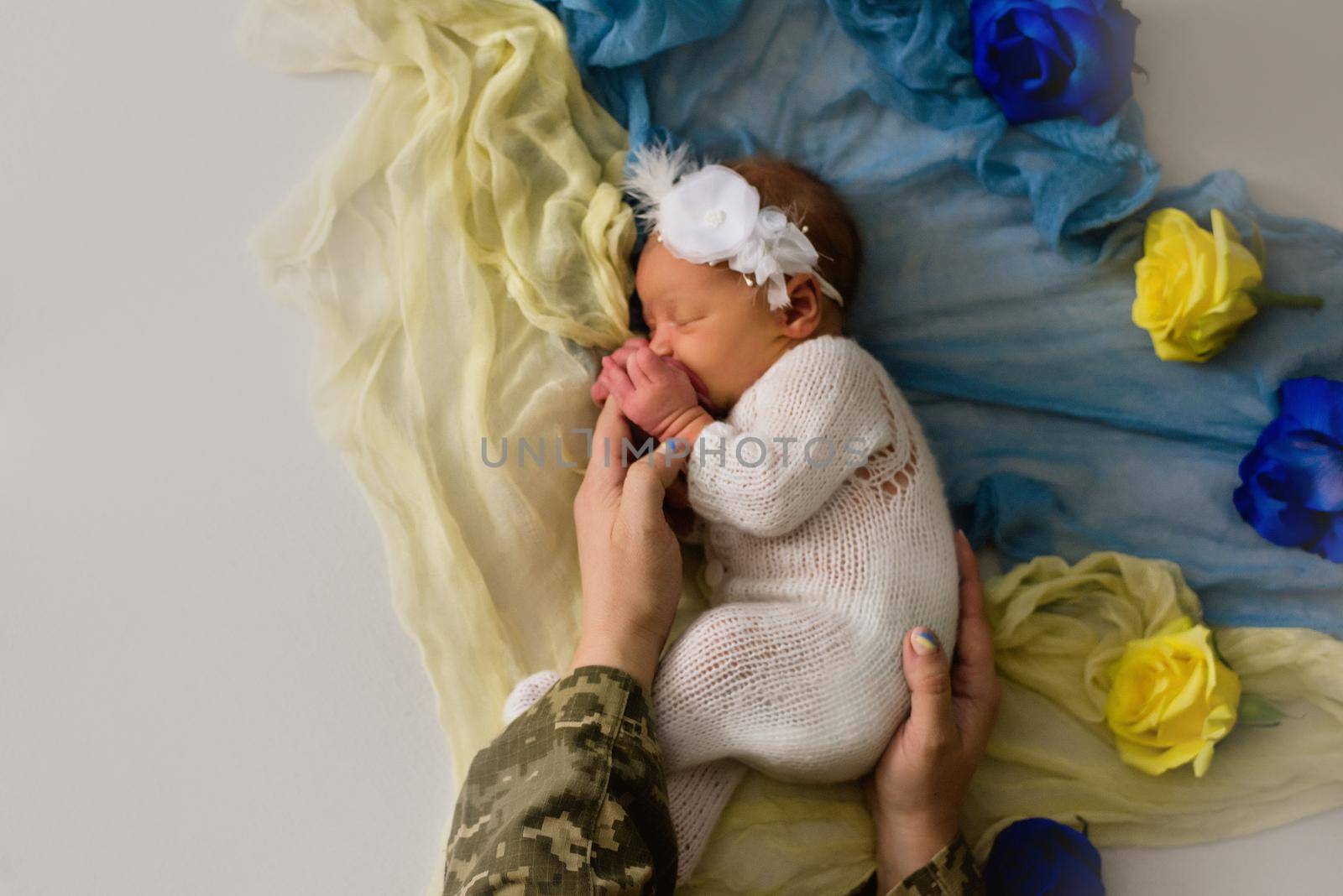 Ukrainian newborn in the studio patriotic blue yellow colors during the war in Ukraine 2022. A little baby, girl sleeps with mother military