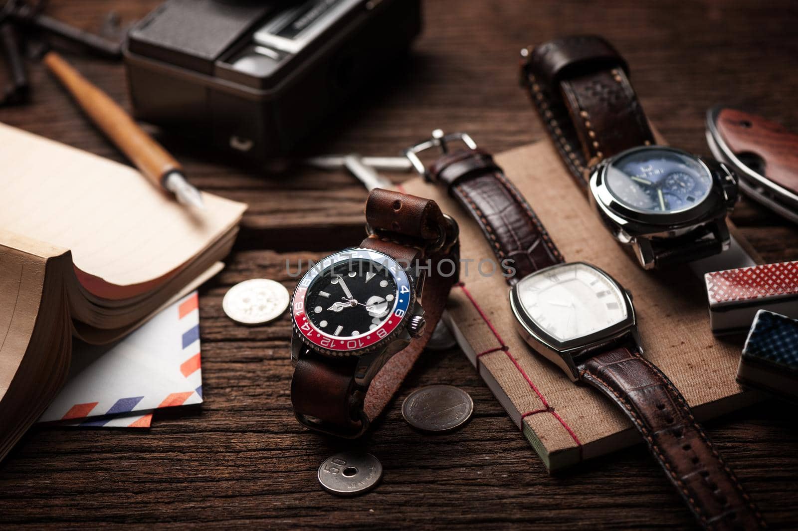 closeup luxury wristwatch for men with black dial blue-red bezel and leather strap. wristwatch with vintage men's objects.