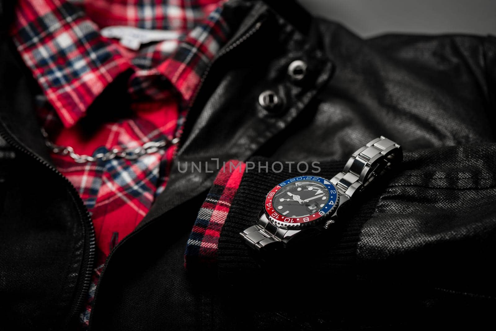 closeup luxury wristwatch for men with black dial blue-red bezel and stainless steel bracelet.