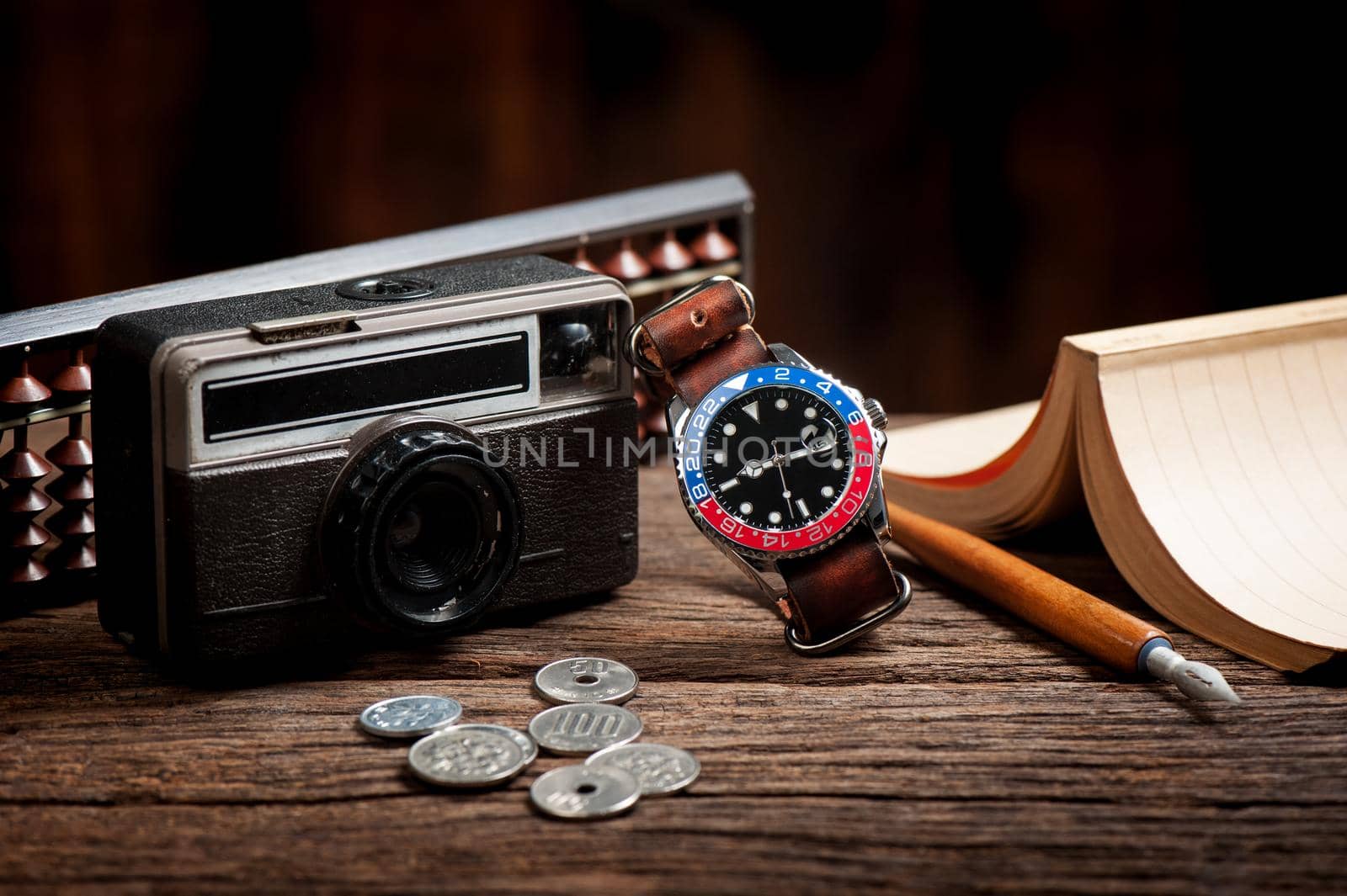 closeup luxury wristwatch for men with black dial blue-red bezel and leather strap.