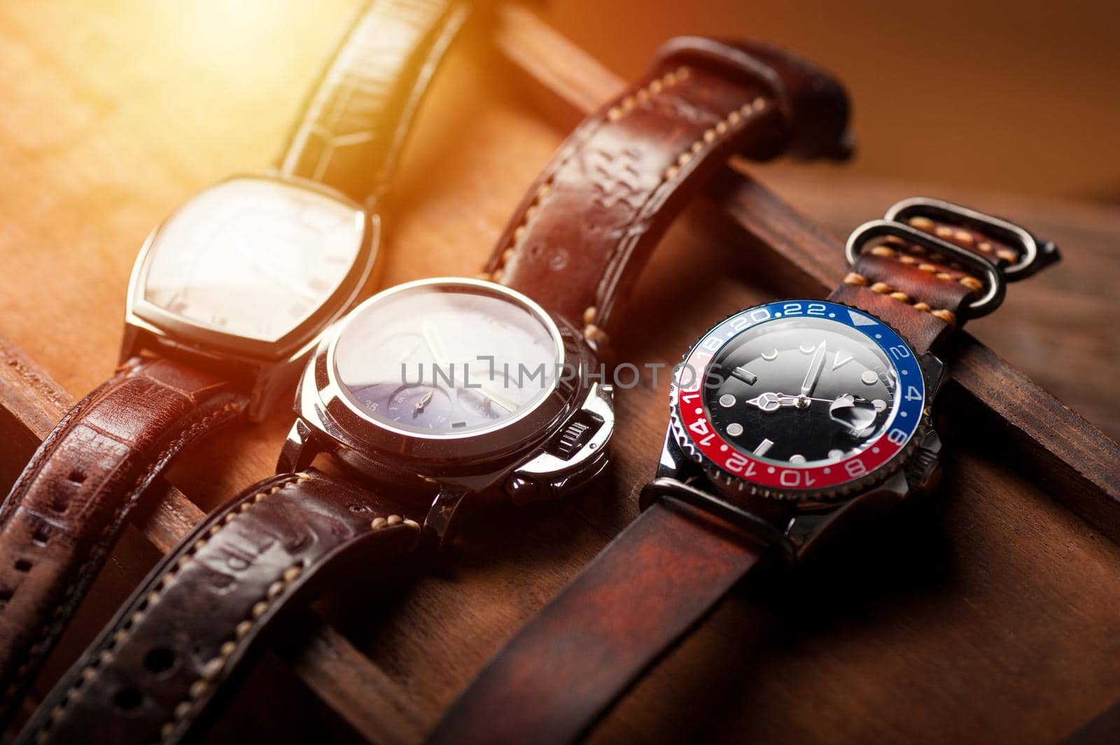 closeup luxury wristwatch for men with black dial blue-red bezel and leather strap. wristwatch with vintage men's objects.