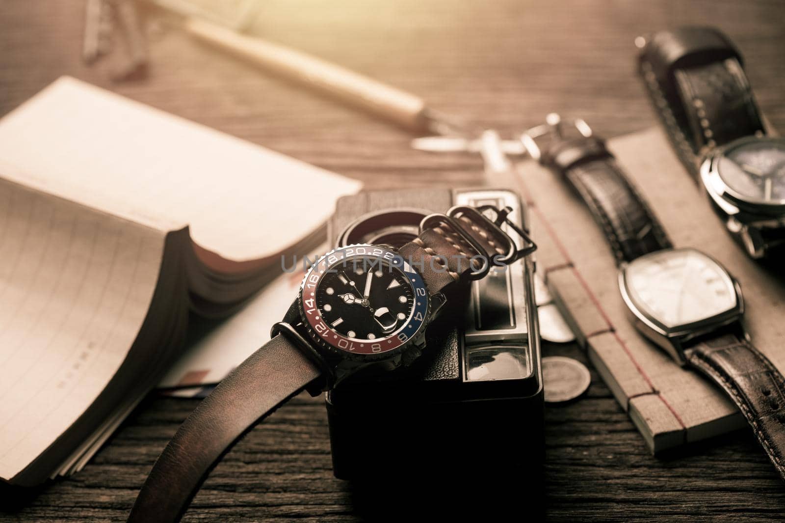 closeup luxury wristwatch for men with black dial blue-red bezel and leather strap. wristwatch with vintage men's objects.