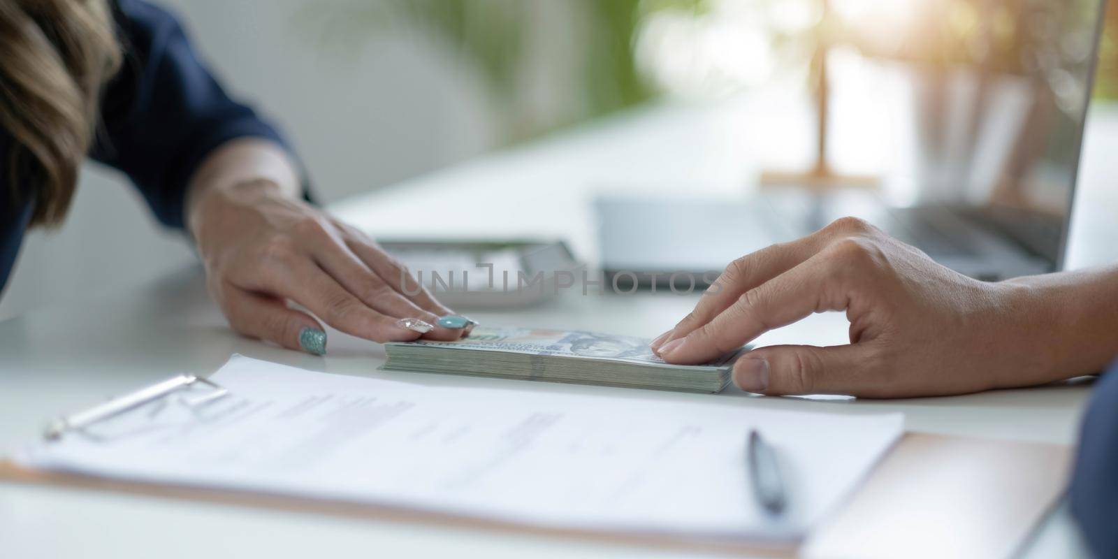 Businessman giving of money, cash dollars to his partner over an office desk - loan, payment and bribery concepts.