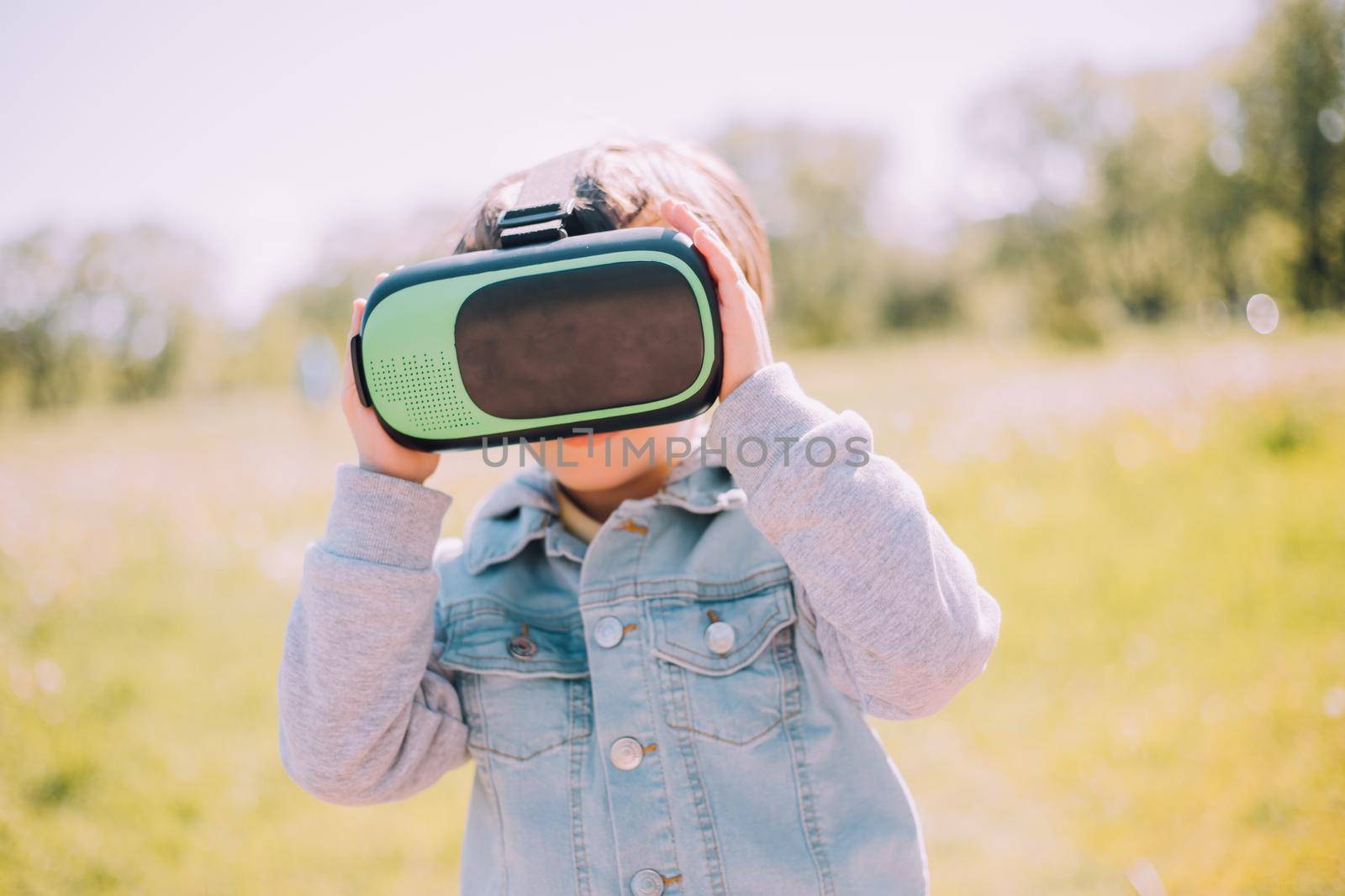 A boy is playing virtual reality glasses on the street . Modern gadgets. Children's games. The choice of virtual glasses. An article about virtual glasses. Modern children. Copy Space