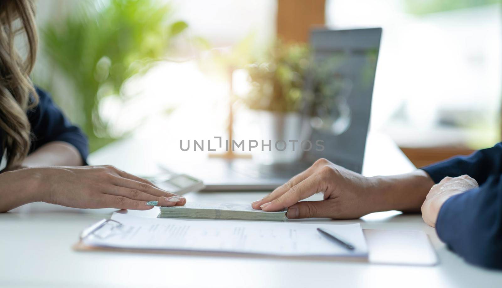 Businessman giving of money, cash dollars to his partner over an office desk - loan, payment and bribery concepts by wichayada