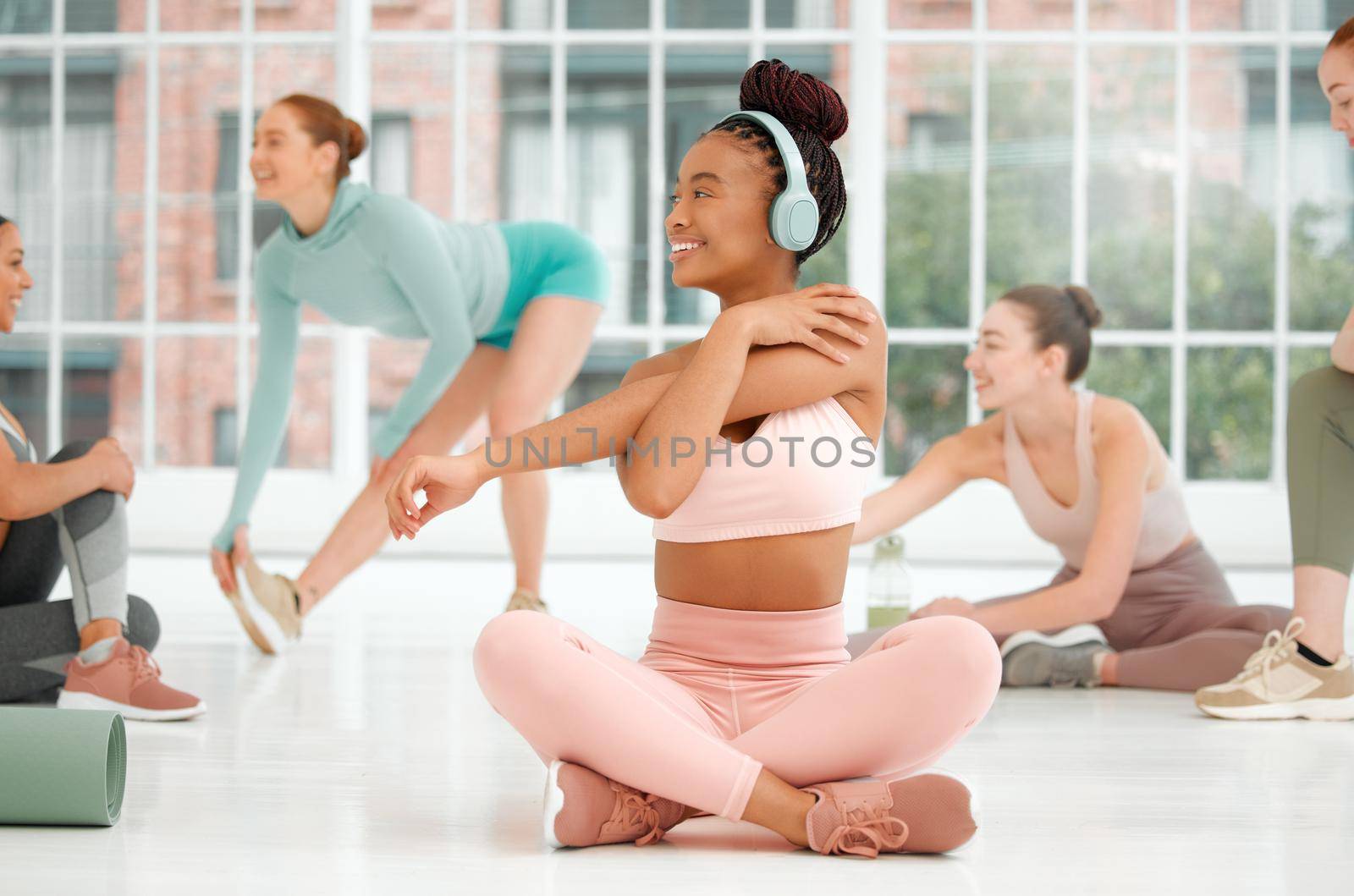 Now this is something youd want to be a part of. a young woman wearing headphones while stretching. by YuriArcurs