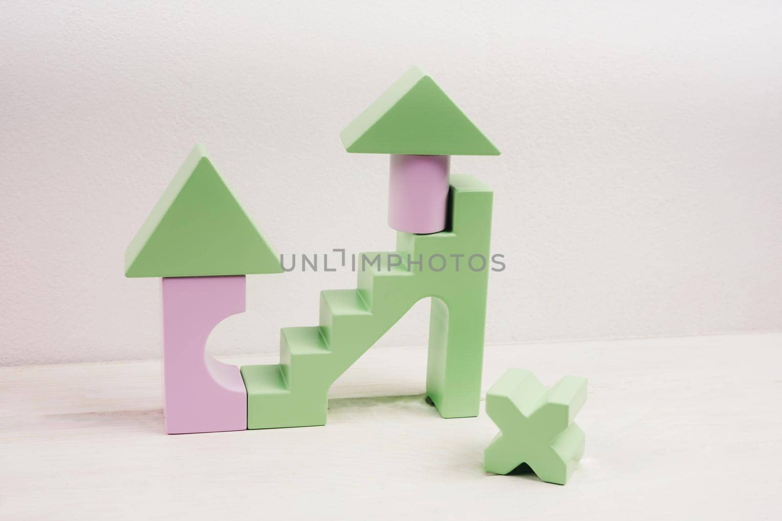 Children's wooden construction kit. Toys made of natural material. Figures from a lilac and green wooden construction. Popular colors 2022 - very peri. Toy for developing a child's creative thinking.